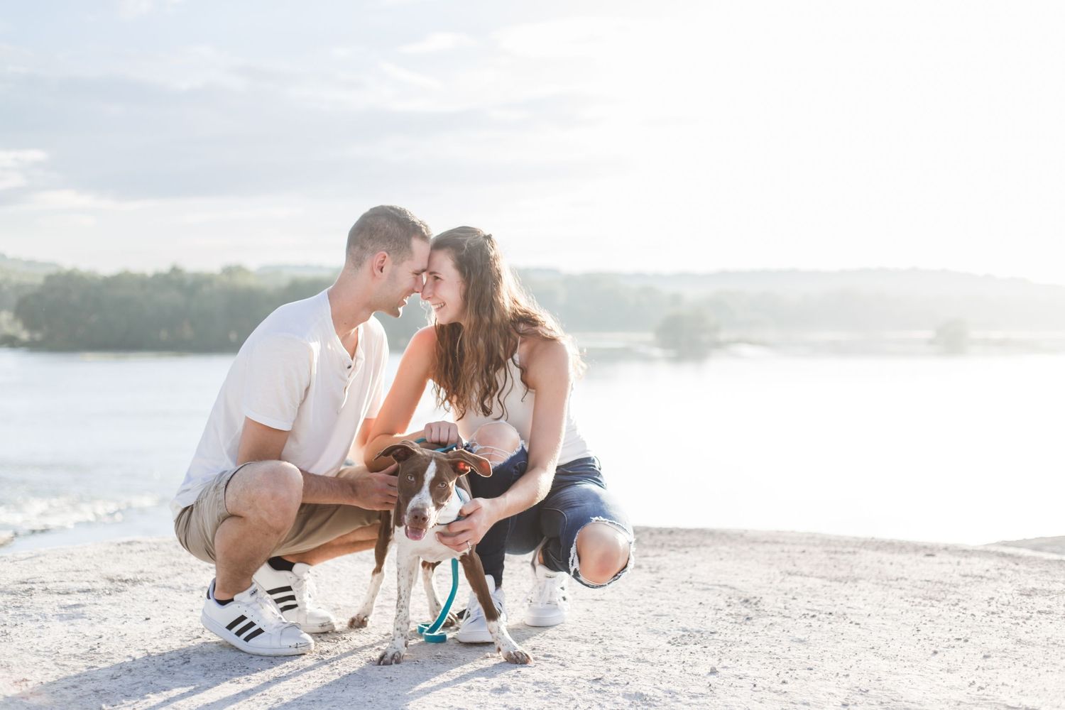 A romantic couple embraces against a backdrop of white chalky cliffs on a bright sunny day.
