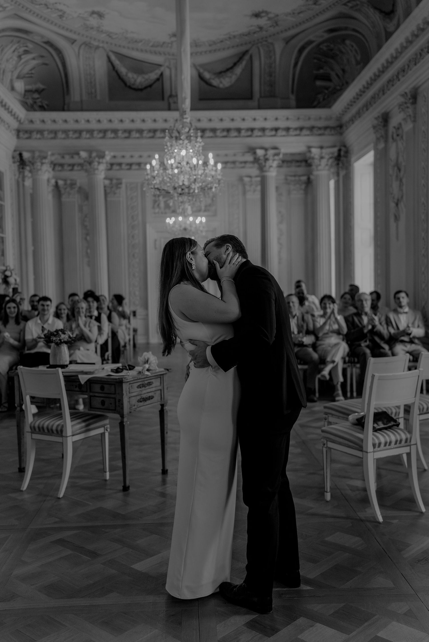 Schwarz-Weiß-Foto eines Paares, das sich während einer eleganten Hochzeitszeremonie in einem prachtvollen Ballsaal zum ersten Mal als paar