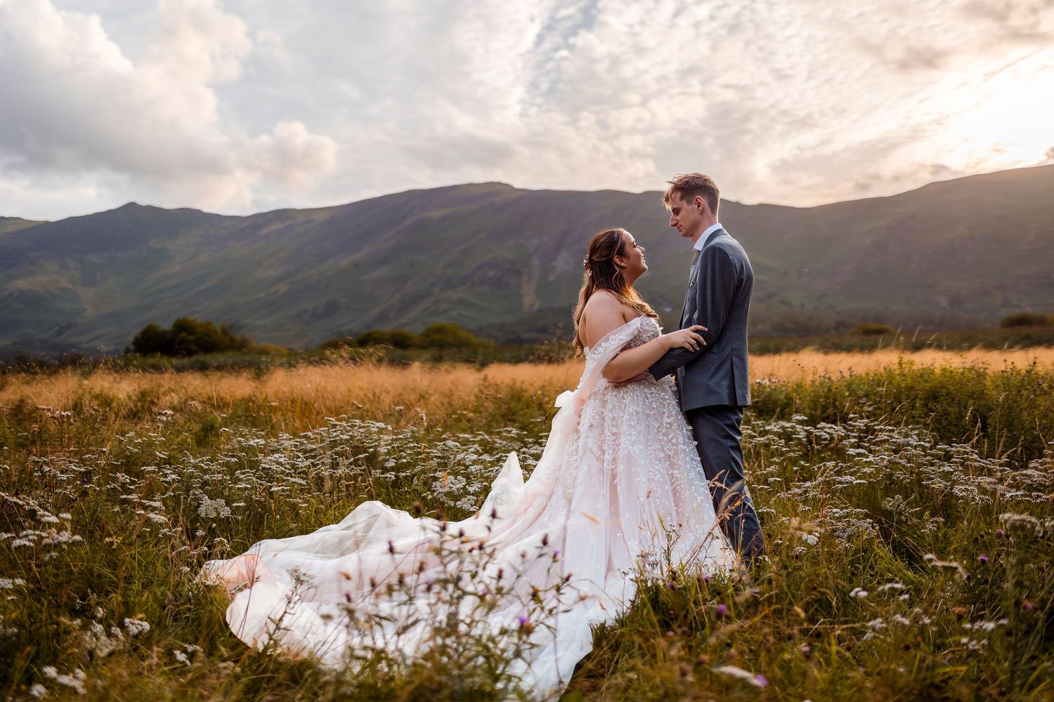 Joyful newlyweds celebrate with raised hands walking down the aisle, bride holding bouquet, guests cheering outdoors.