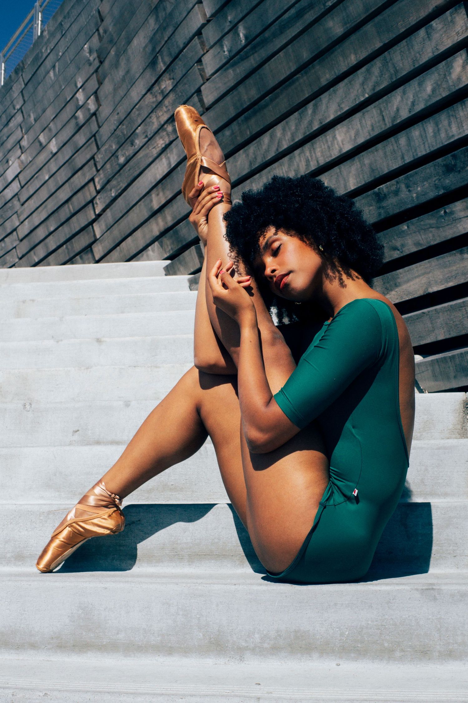 professional dance photographer with black ballerina in seattle in green leotard and pointe shoes portrait
