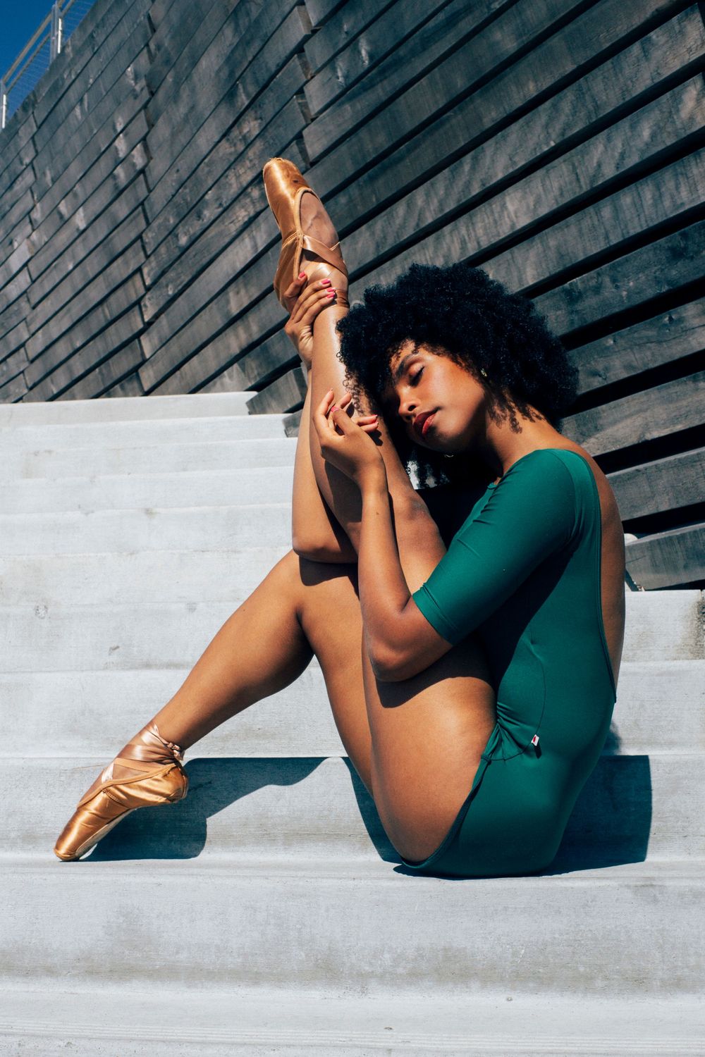 professional dance photographer with black ballerina in seattle in green leotard and pointe shoes portrait