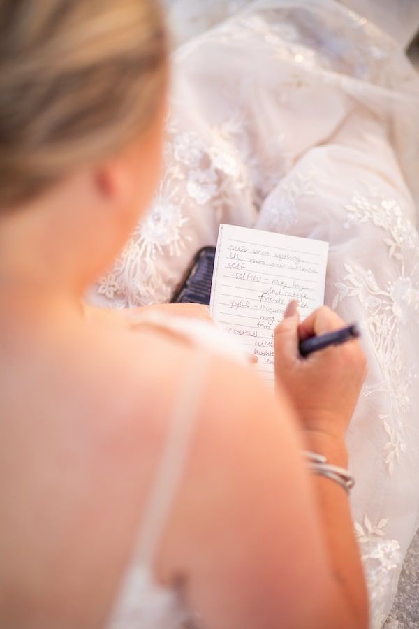 Close-up view of someone writing on paper with delicate white lace fabric in the background.