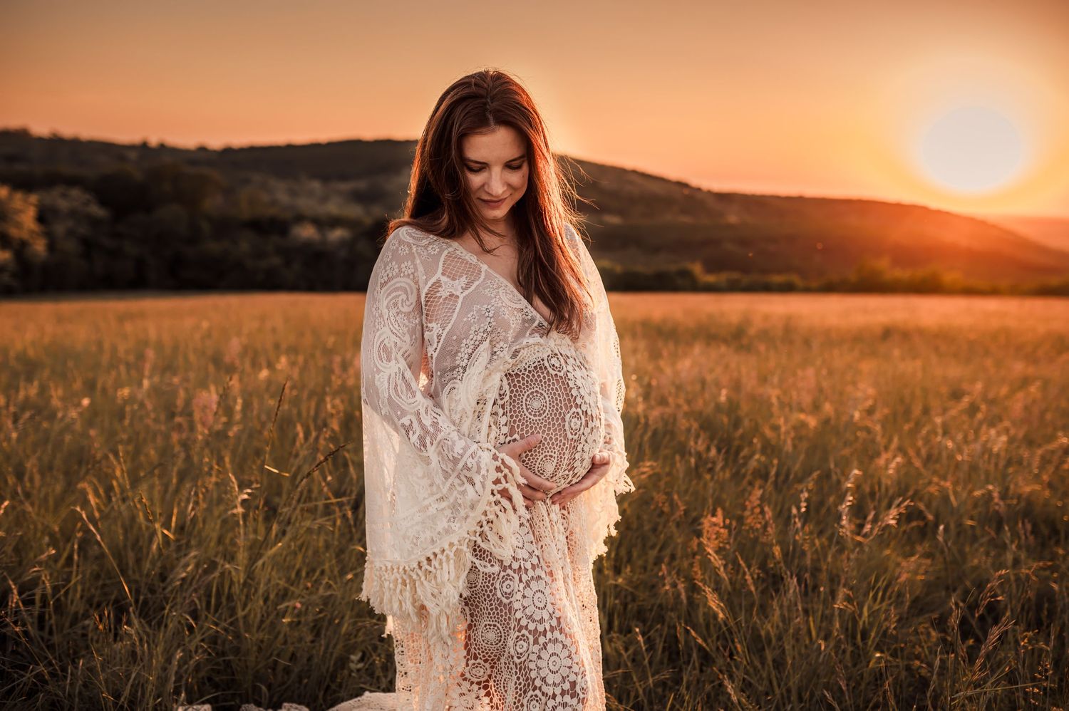 A delicate lace dress catches the golden light in a field during sunset, creating a dreamy and romantic scene.