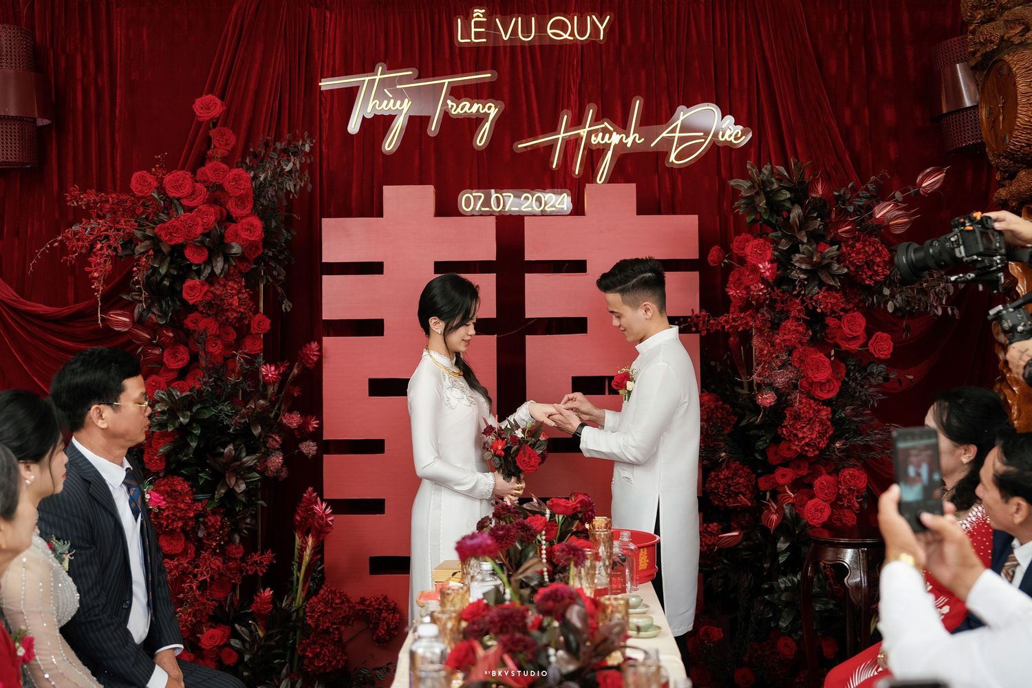 Traditional Asian tea ceremony with red flower backdrop and double happiness symbol.