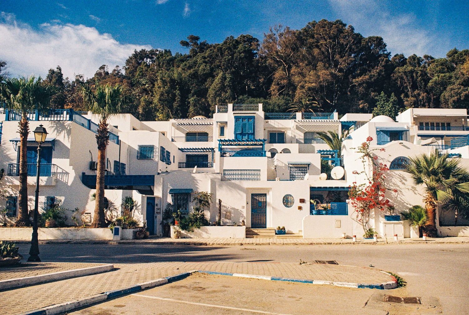 White Mediterranean-style resort buildings with blue accents nestled along a sunny beachfront in Tunisia.