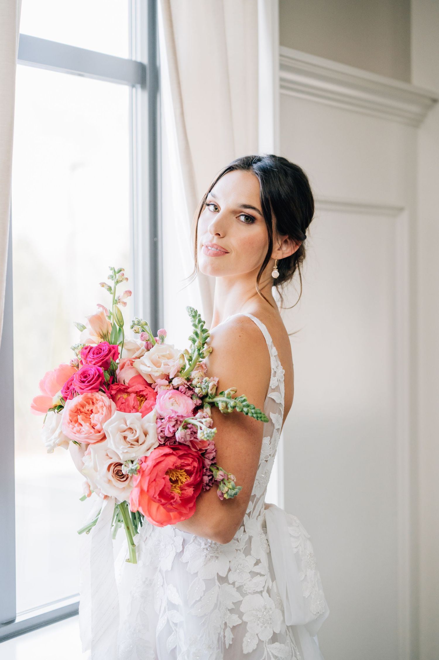 Ethereal wedding dress with delicate floral appliques and sheer details photographed in soft natural window light.