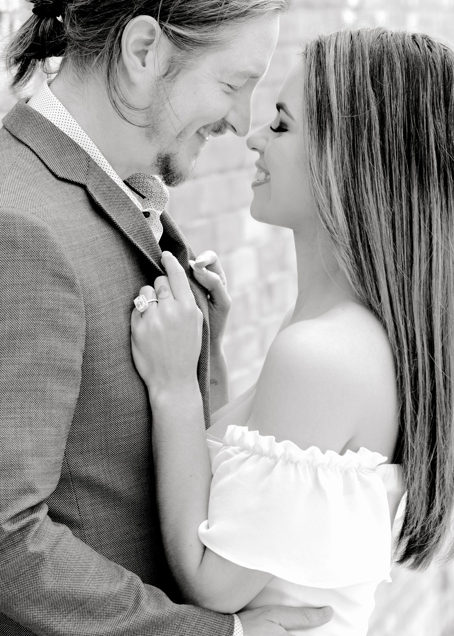 A romantic black and white portrait of a couple in wedding attire sharing an intimate moment.