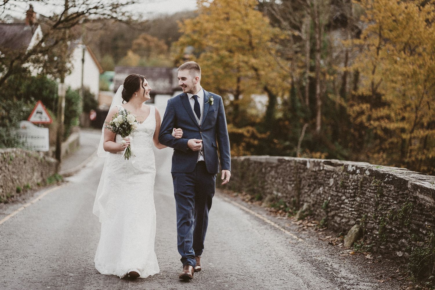 Bride and groom at Autumn walking across river bank