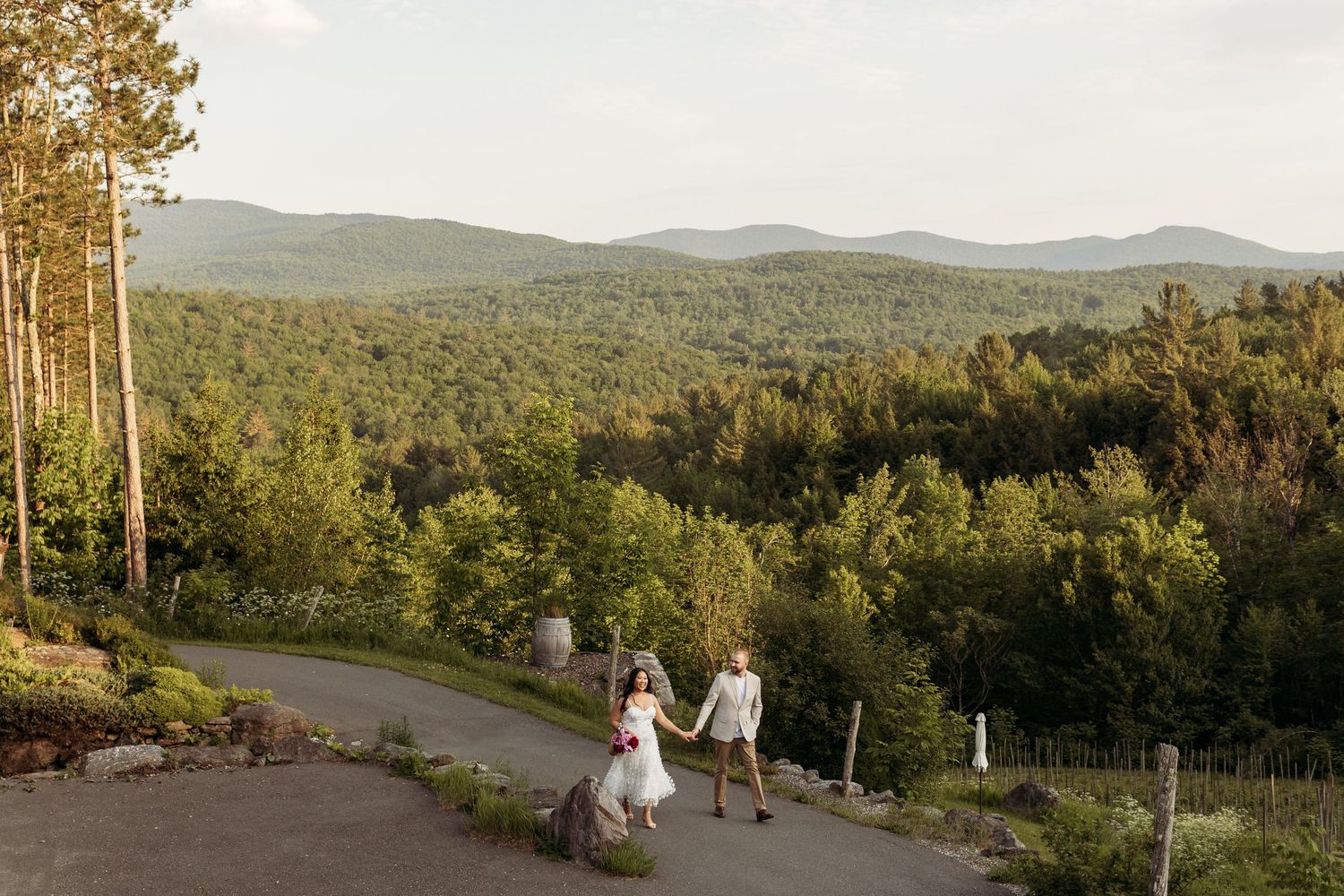 A couple holding hands and walking through Chateau St Agnes vineyards during a sunset on a summer day. Aliza Dworkind Photography
