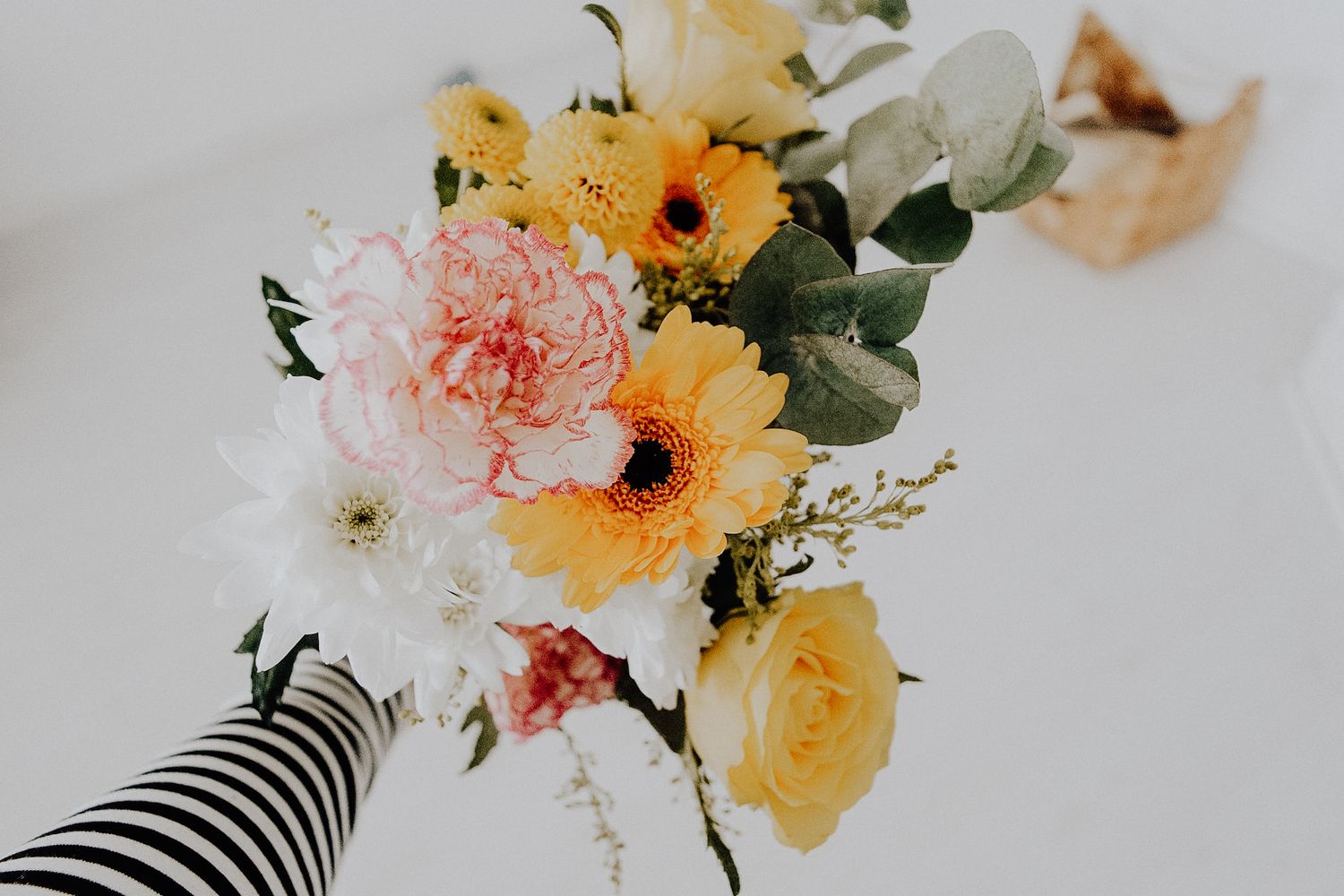 Delicate peach and yellow floral arrangements with eucalyptus leaves styled against a light neutral background.