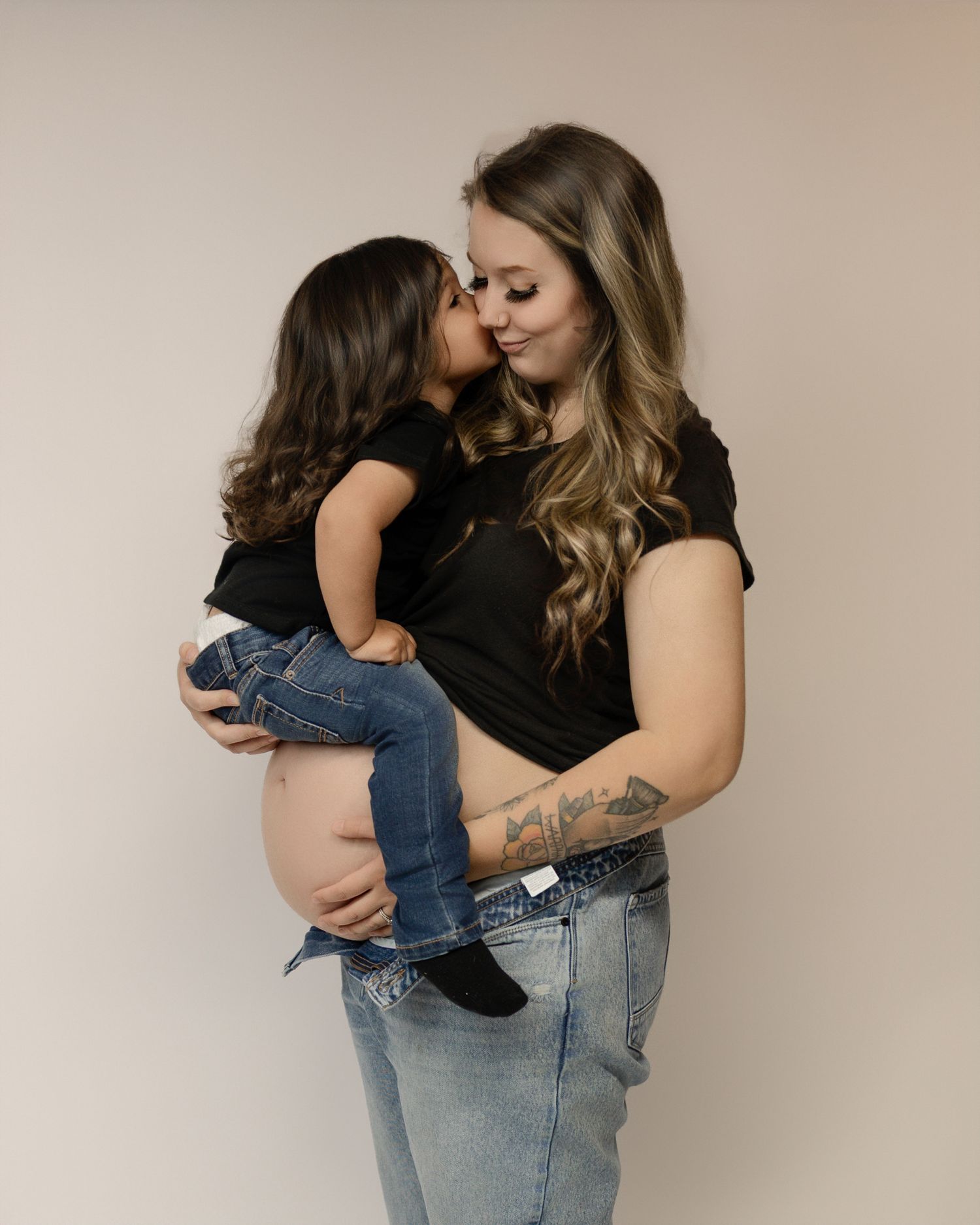 Parent wearing light denim jeans and black top holds small child in progressive sequence of affectionate poses.