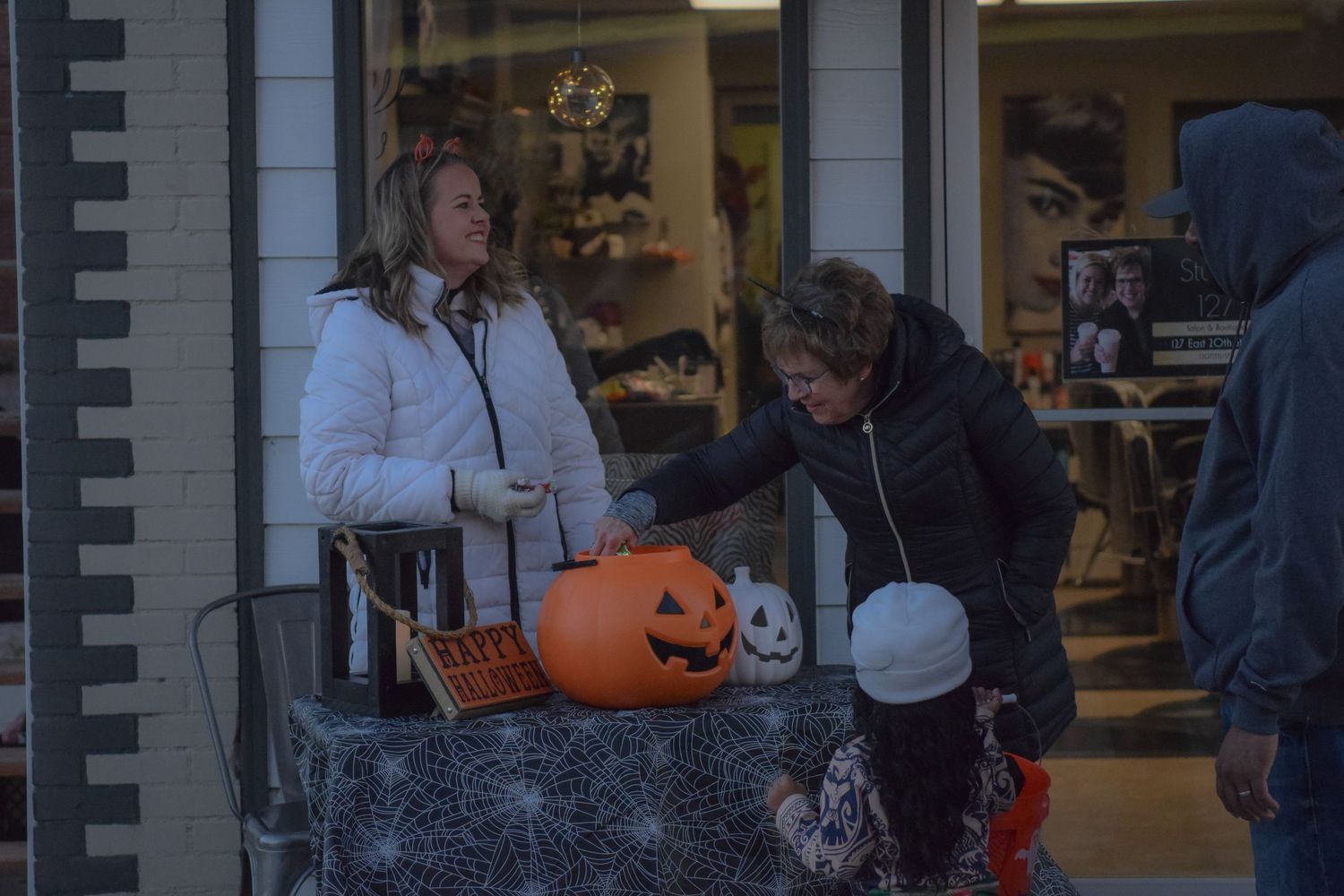 Halloween decorations and trick-or-treat setup outside a storefront with pumpkins and spooky props.