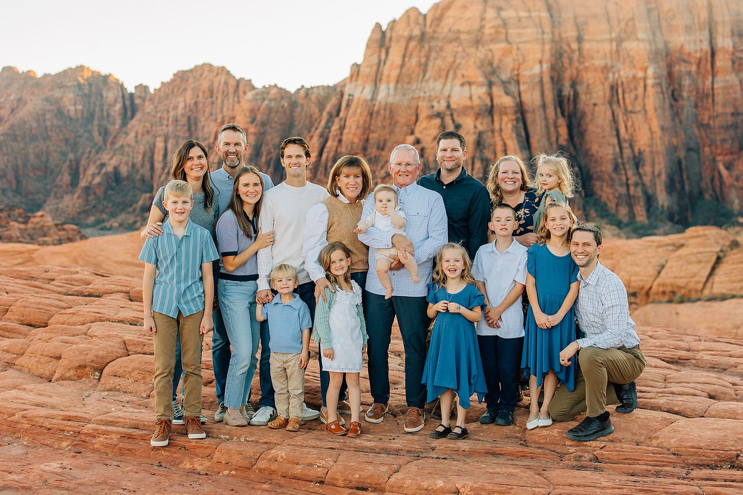Family group photos captured against stunning red rock formations in a desert landscape at sunset.