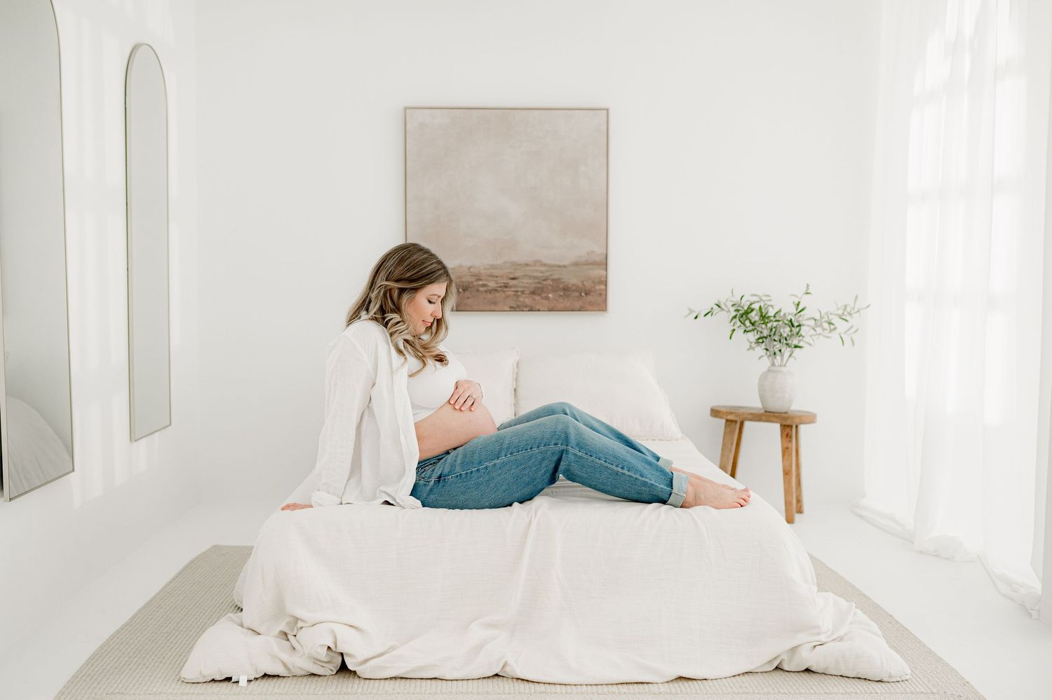 Cozy white bedroom with natural light showcasing a comfortable bed with white linens during an Jacksonville, FLmaternity photography session