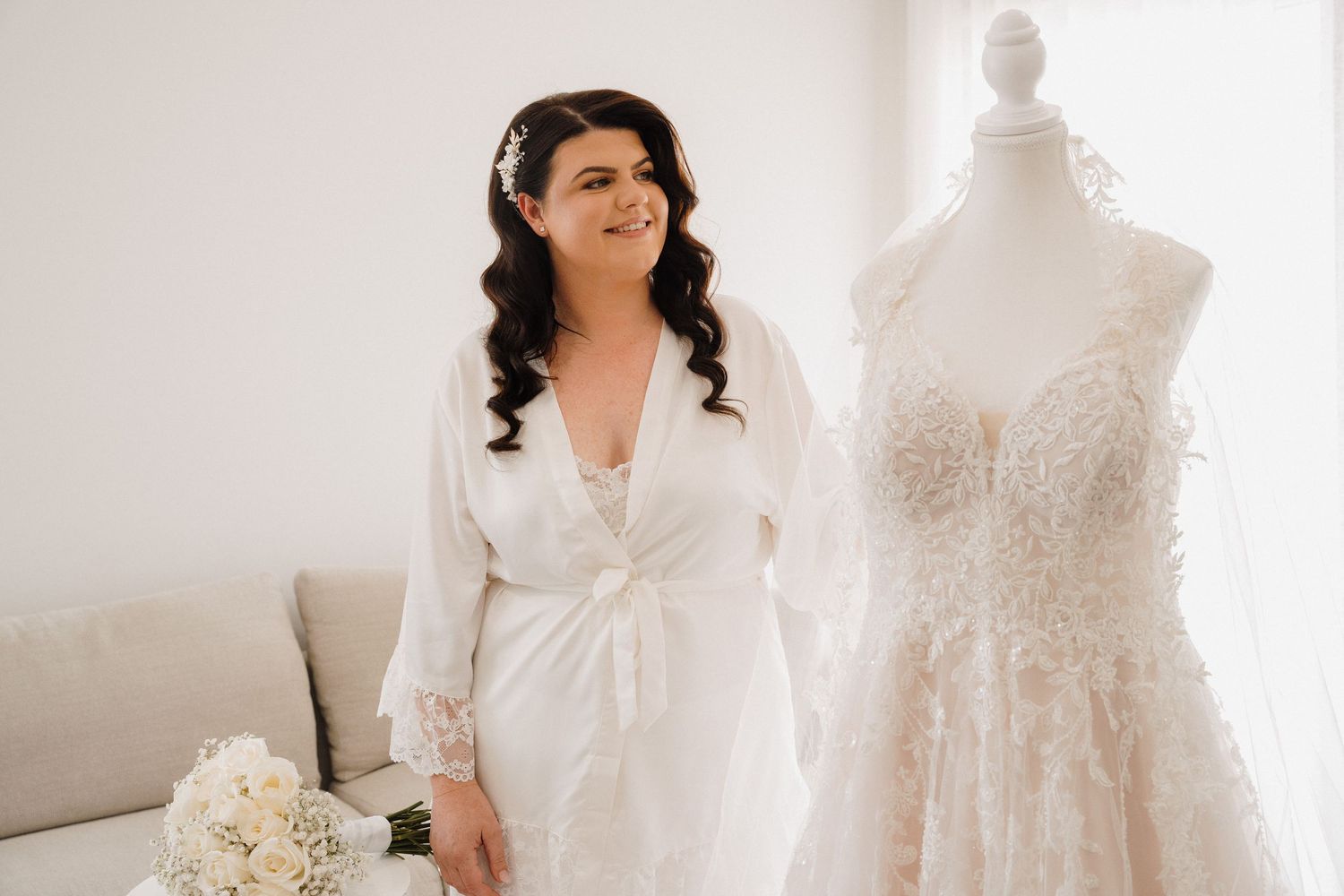 A bridal boutique displays elegant white wedding dresses on mannequins next to floral arrangements.