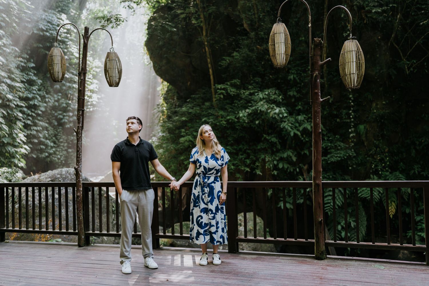 Couple walking and laughing together on stone pathway surrounded by tropical plants.