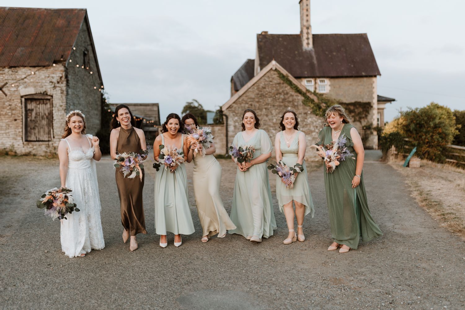 Wedding party in coordinated sage and light blue dresses poses together at Wilde Lodge