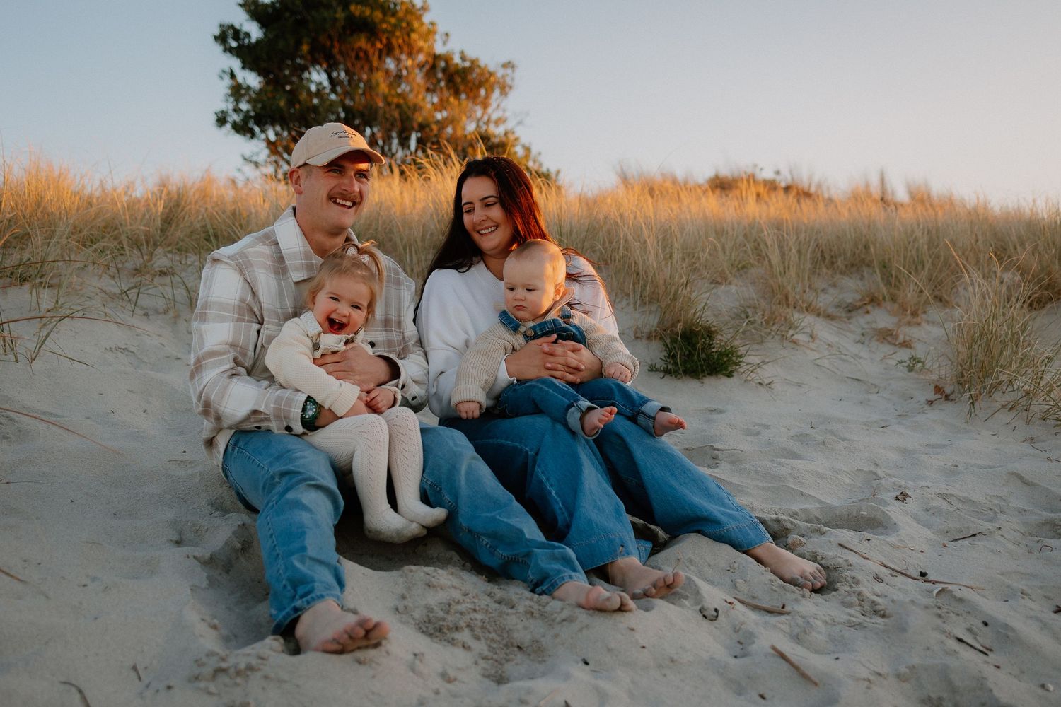 A family of four cuddle and tickle each other for a family photograph