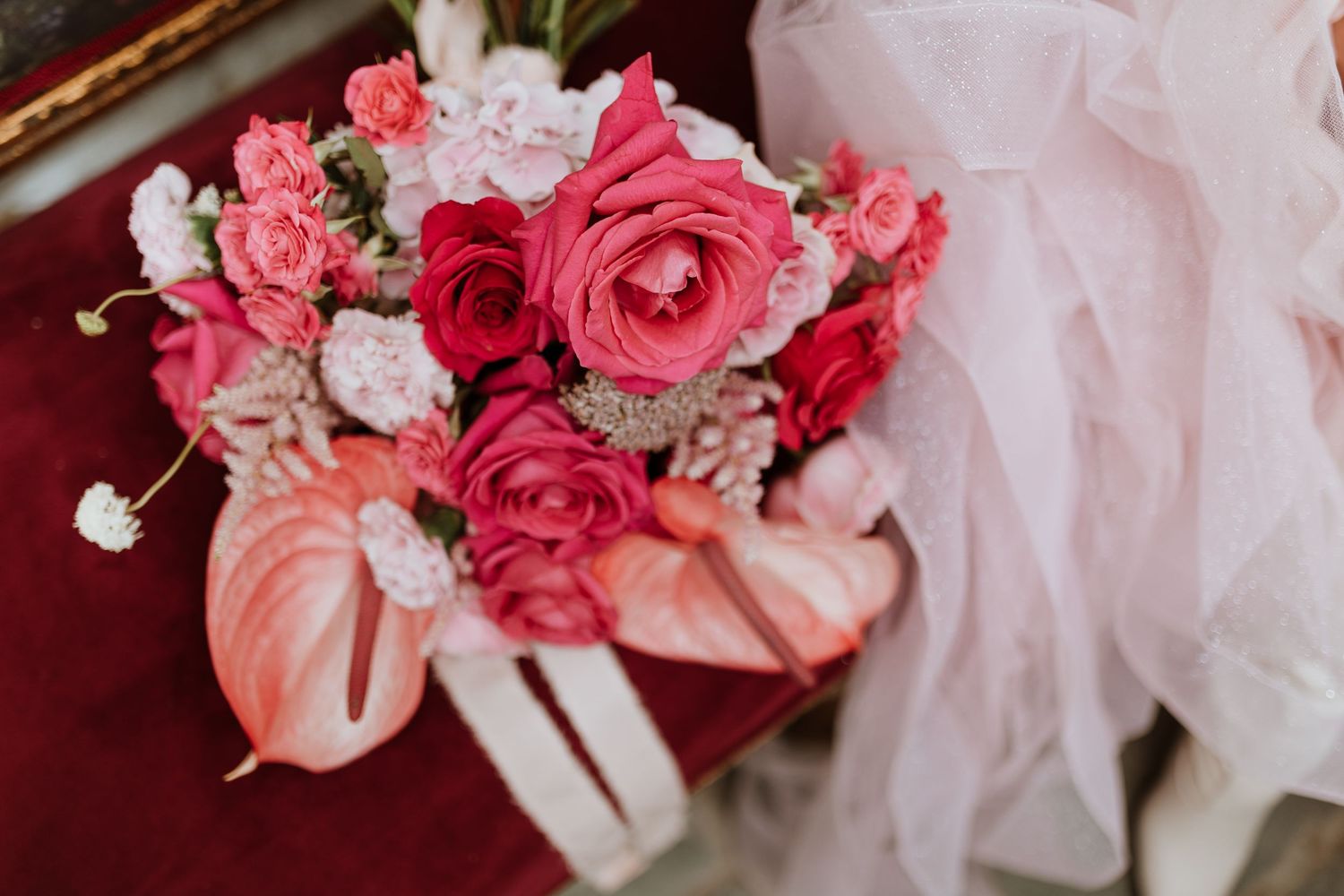 Close-up details of pink and red roses with white tulle fabric creating an elegant bridal or wedding arrangement.