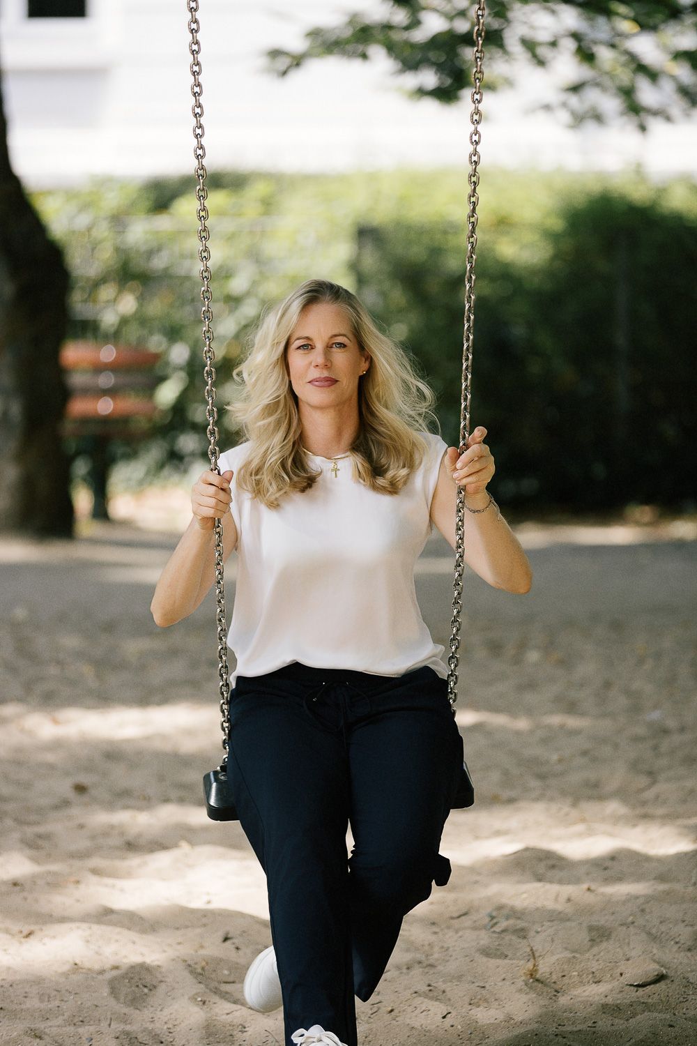 professionelles positives Business-Portrait einer lächelnden freien Rednerin auf der Schaukel für Kinderwillkommensfeste. Businessfotografie