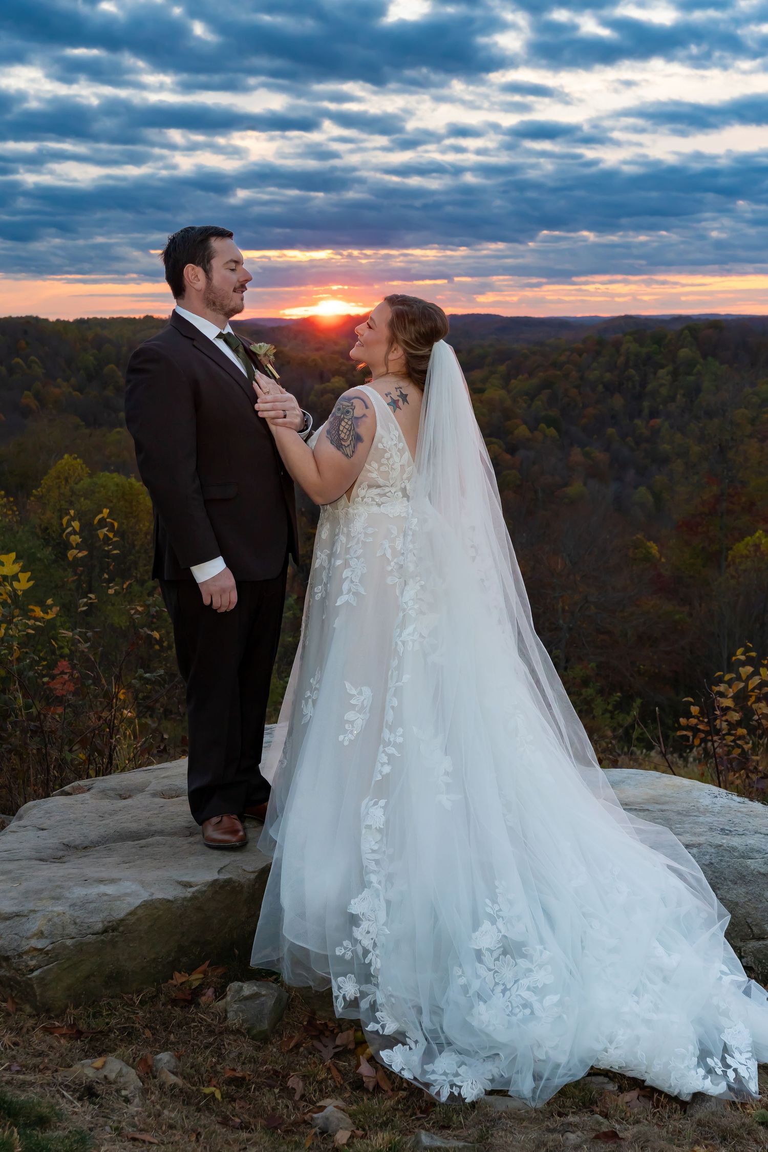 A scenic mountain overlook features a flowing white wedding dress against an autumn landscape and dramatic cloudy sky.