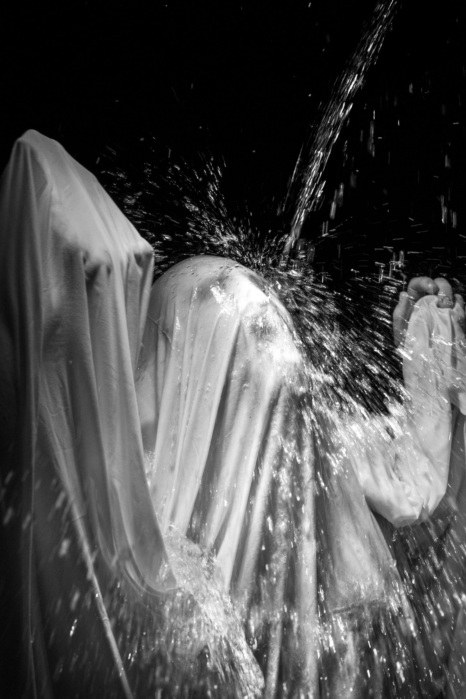 Water splashing against white fabric creating dramatic spray patterns in black and white photography.