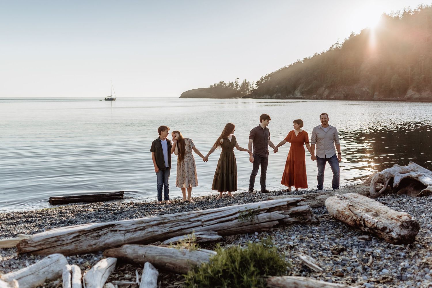 family holds hands on the beach at Bowman Bay while the sun sets behind them