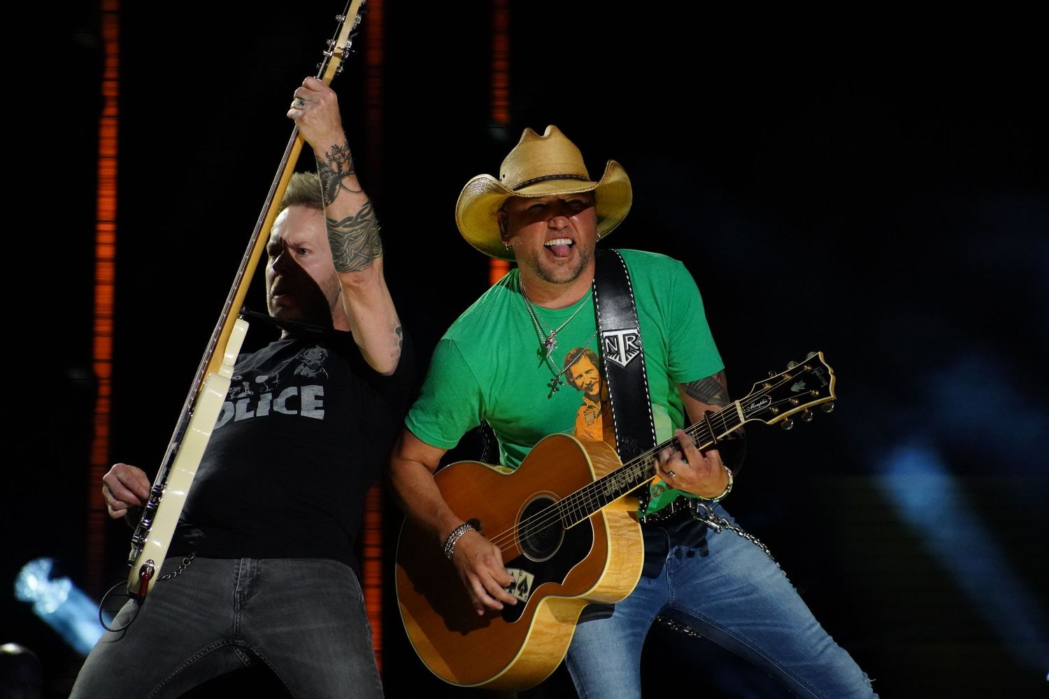 Musicians performing on stage in green outfits with acoustic guitars.