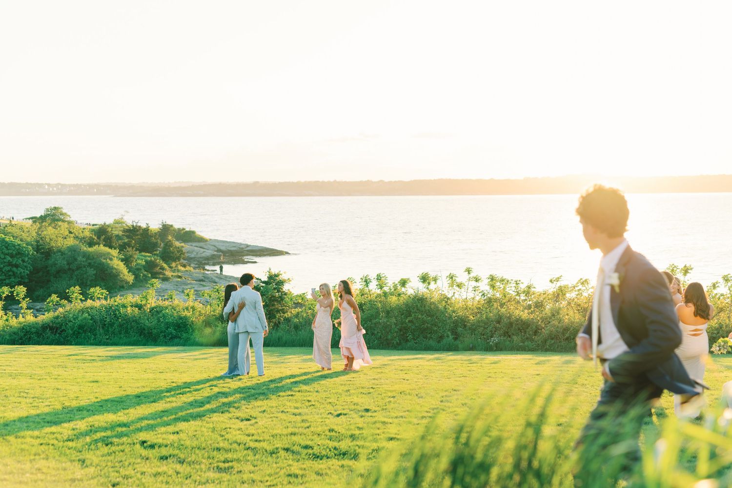 Wedding celebration attendants walk together on stone path with a blue pleated formal gown and black tuxedo.