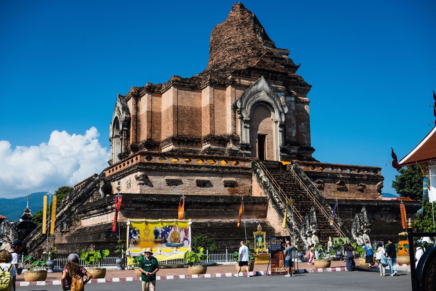 Ancient brick pagoda at Wat Chedi Luang temple in Chiang Mai Thailand with tourists visiting the historic site.