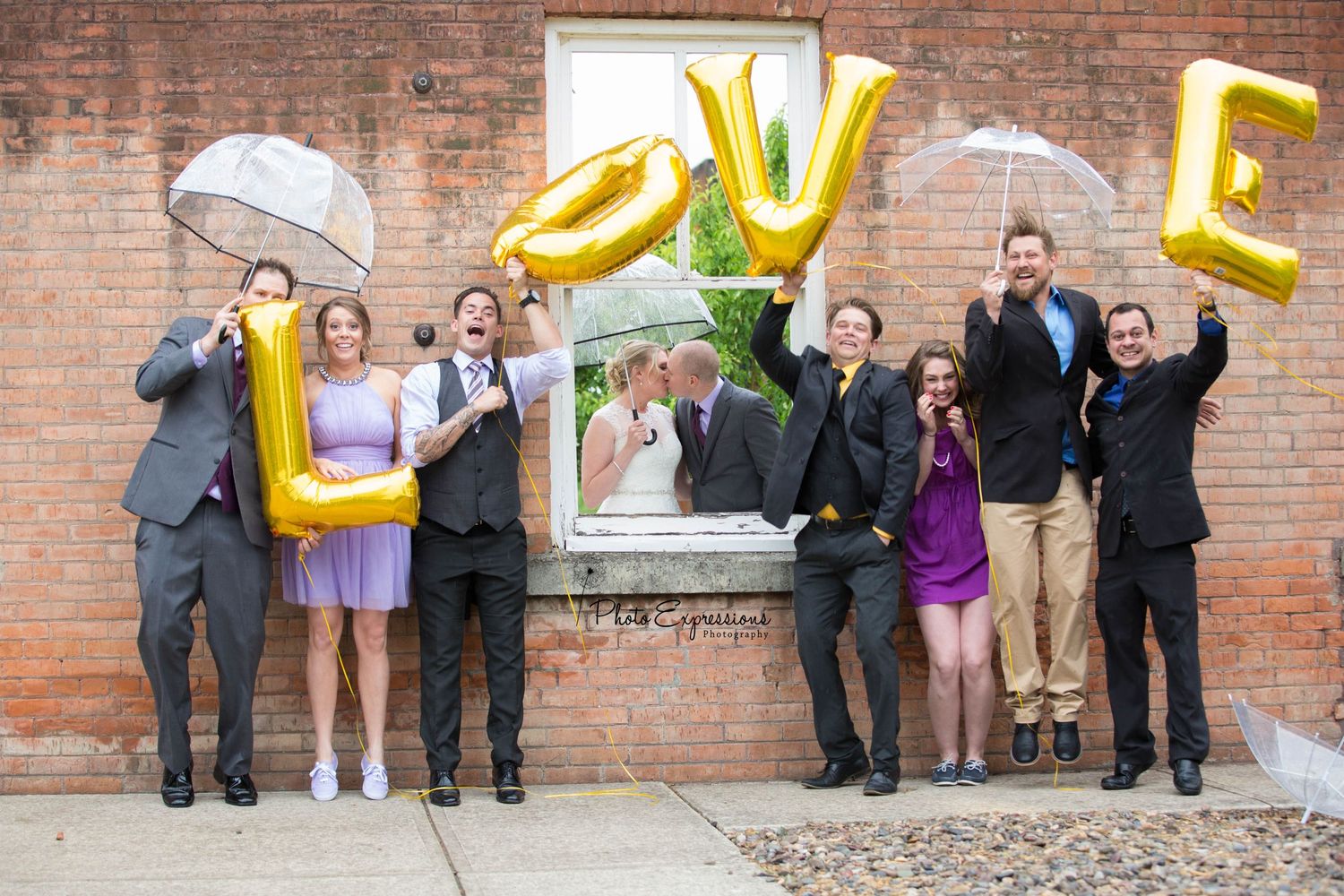 Group photo against brick wall with yellow letter balloons spelling LOVE.