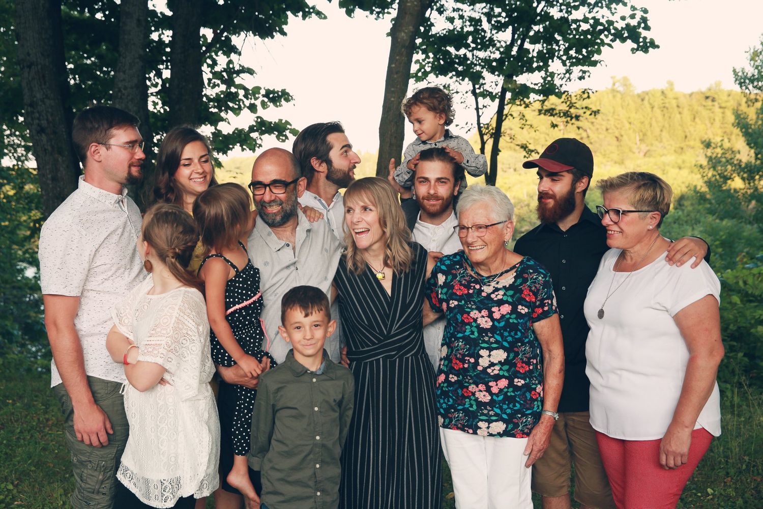 A large family group poses together outdoors for a casual summer portrait.