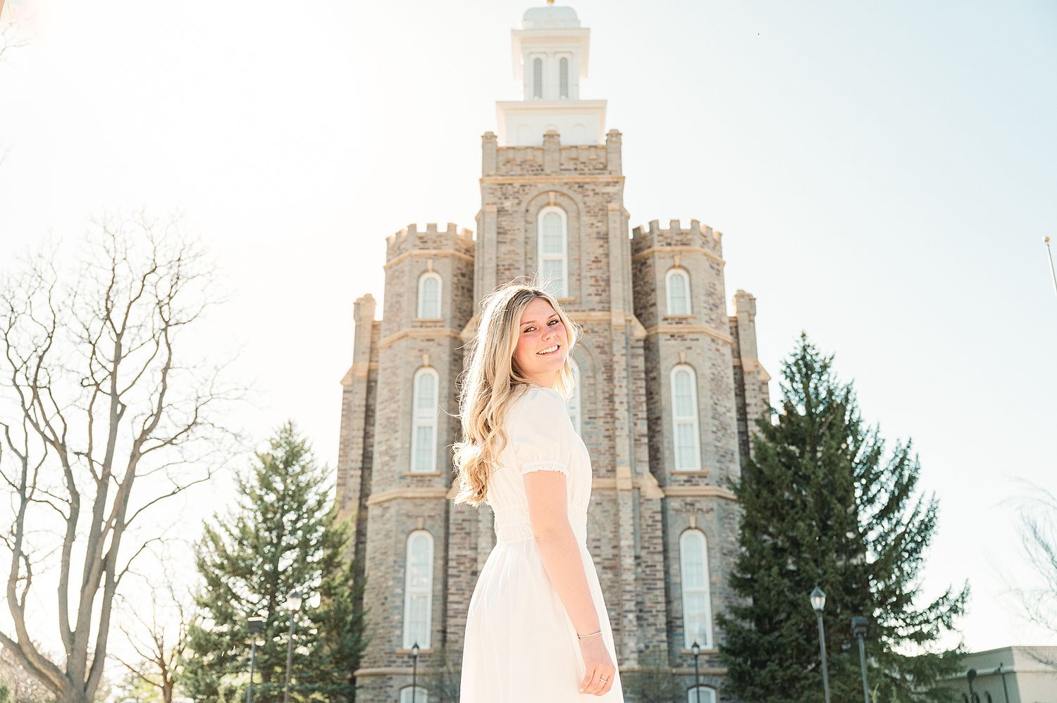 Elegant white dress photographed against towering stone temple architecture at sunset.