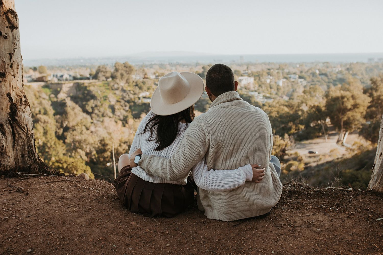 Couple in warm sweaters sitting together overlooking scenic vista of Los Angeles at Will Rogers State Park.