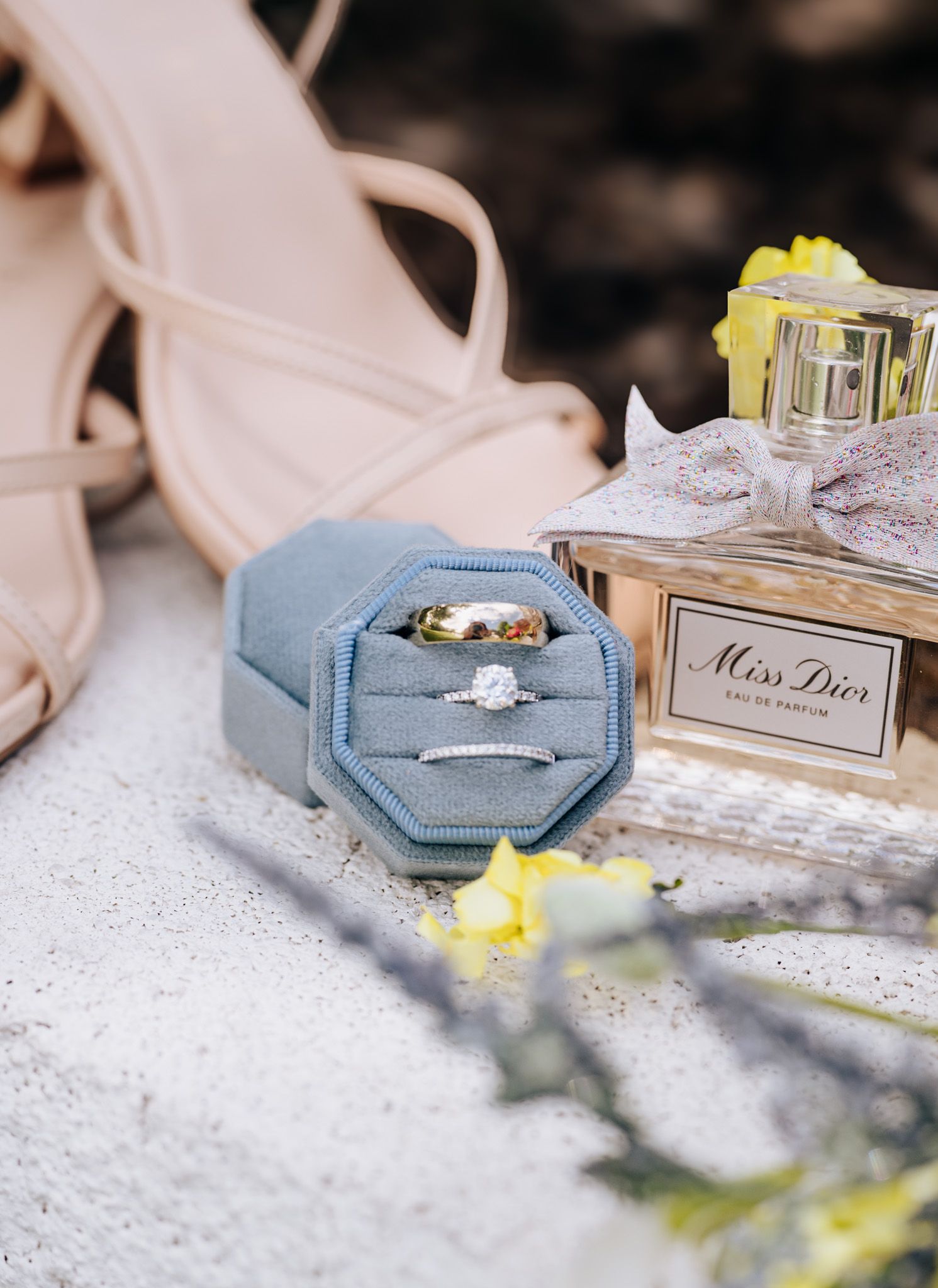 A series of Miss Dior perfume bottles in light blue packaging displayed on a glittery surface with soft bokeh effect.