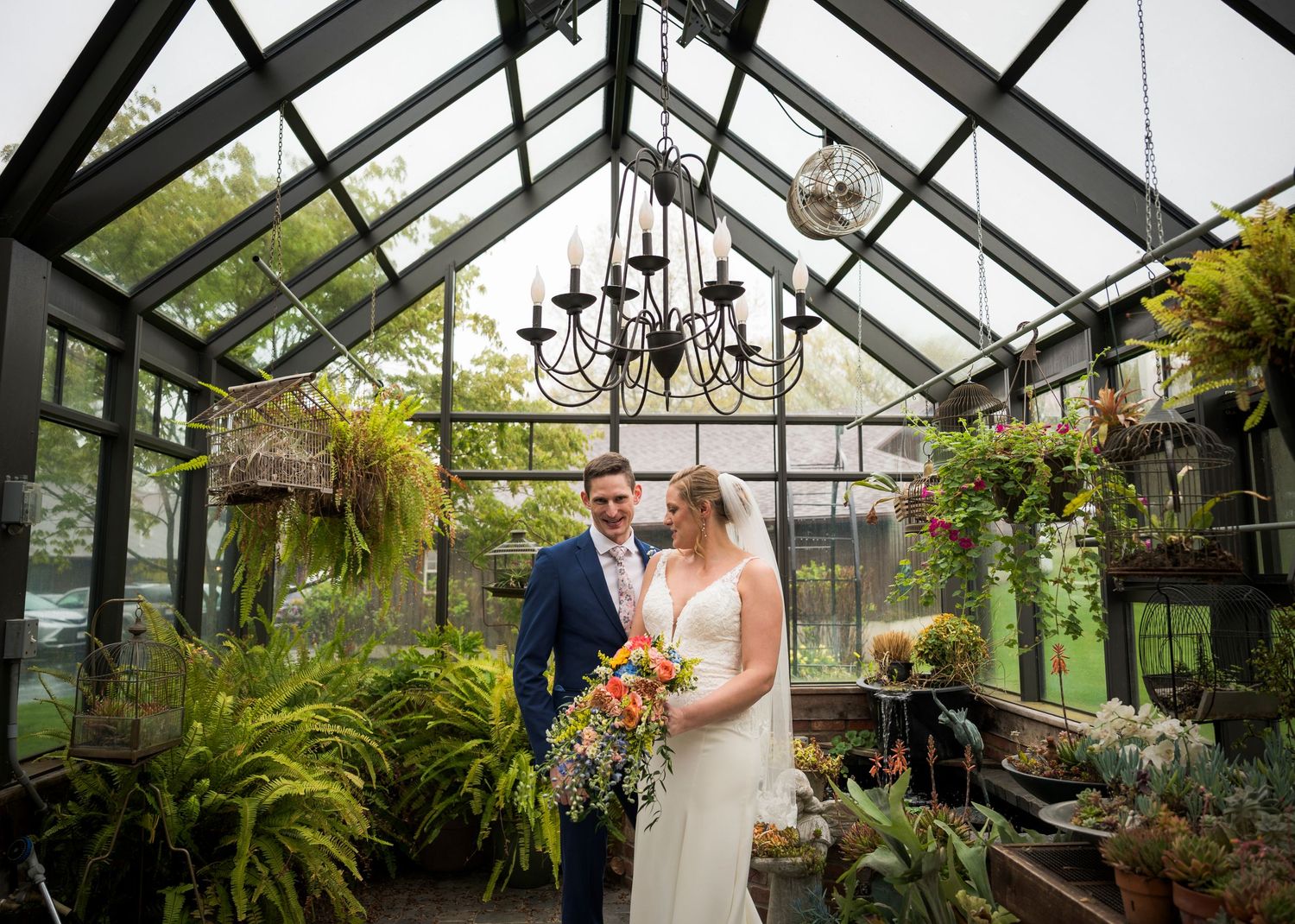 Newlyweds share an intimate moment outdoors with autumn foliage and rustic architecture in background.