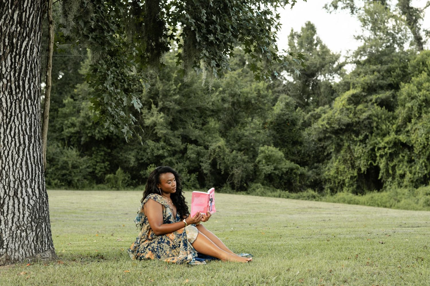 A person in a floral dress poses gracefully on grass during golden hour, creating artistic outdoor portraits.