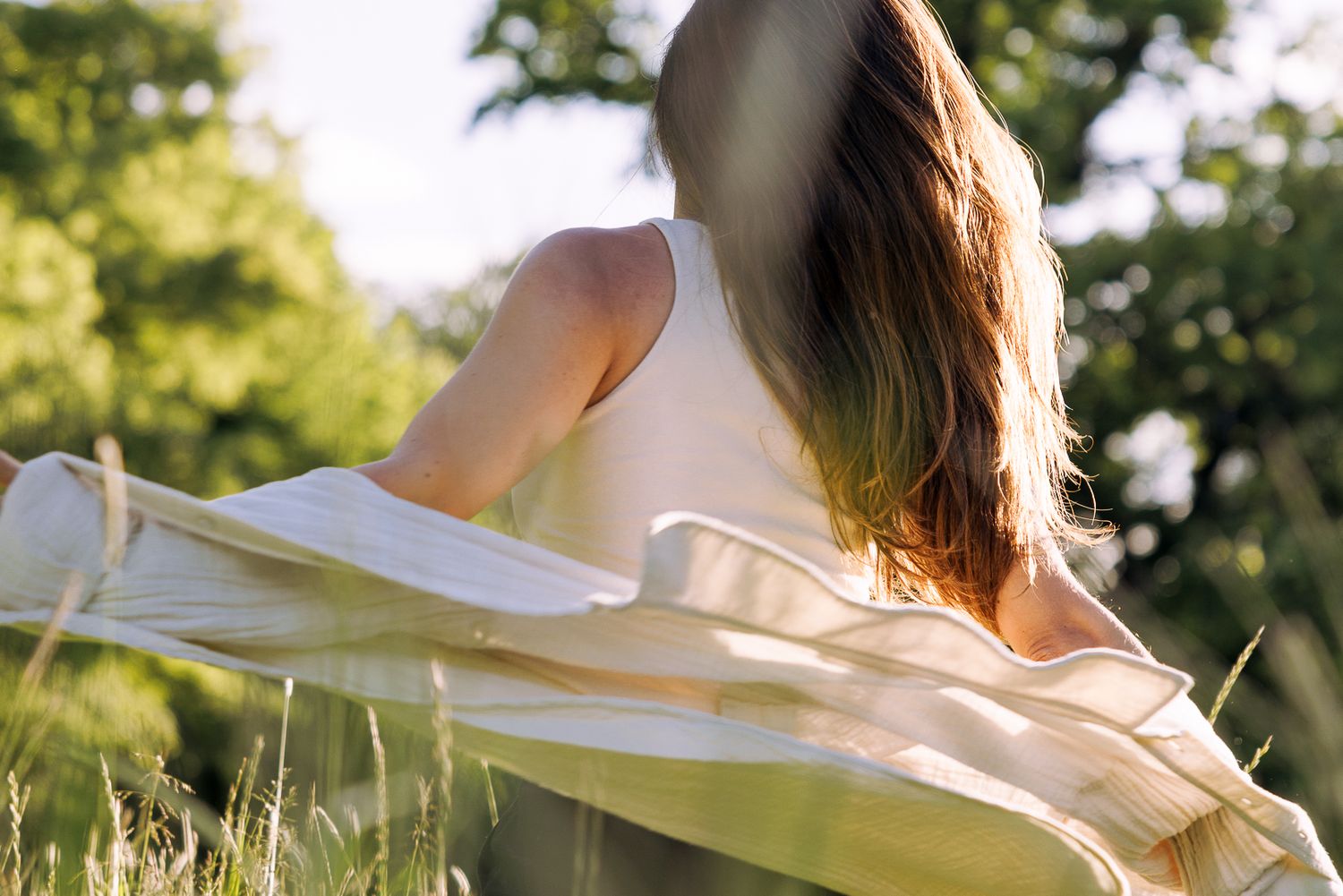 Sunlit portrait crop showing flowing fabric in a natural outdoor setting.