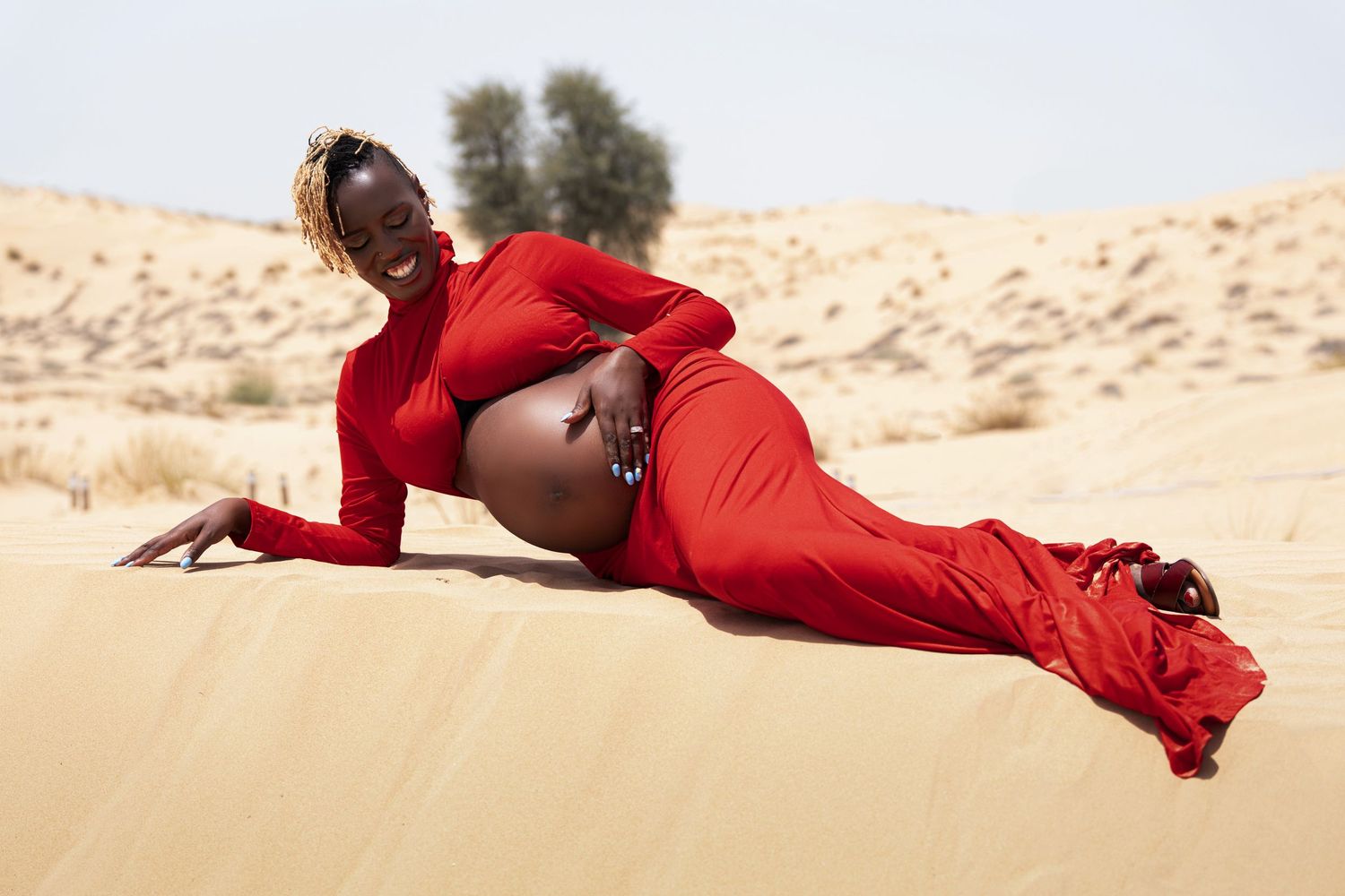 A figure in a flowing red dress poses elegantly across desert sand dunes in artistic shots.