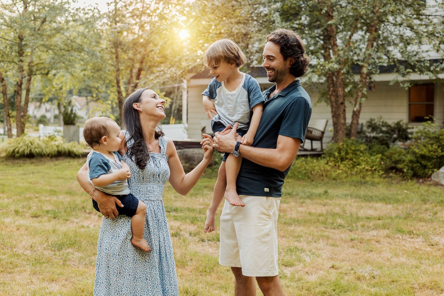 A group enjoys a warm sunset moment together in a grassy backyard during golden hour.