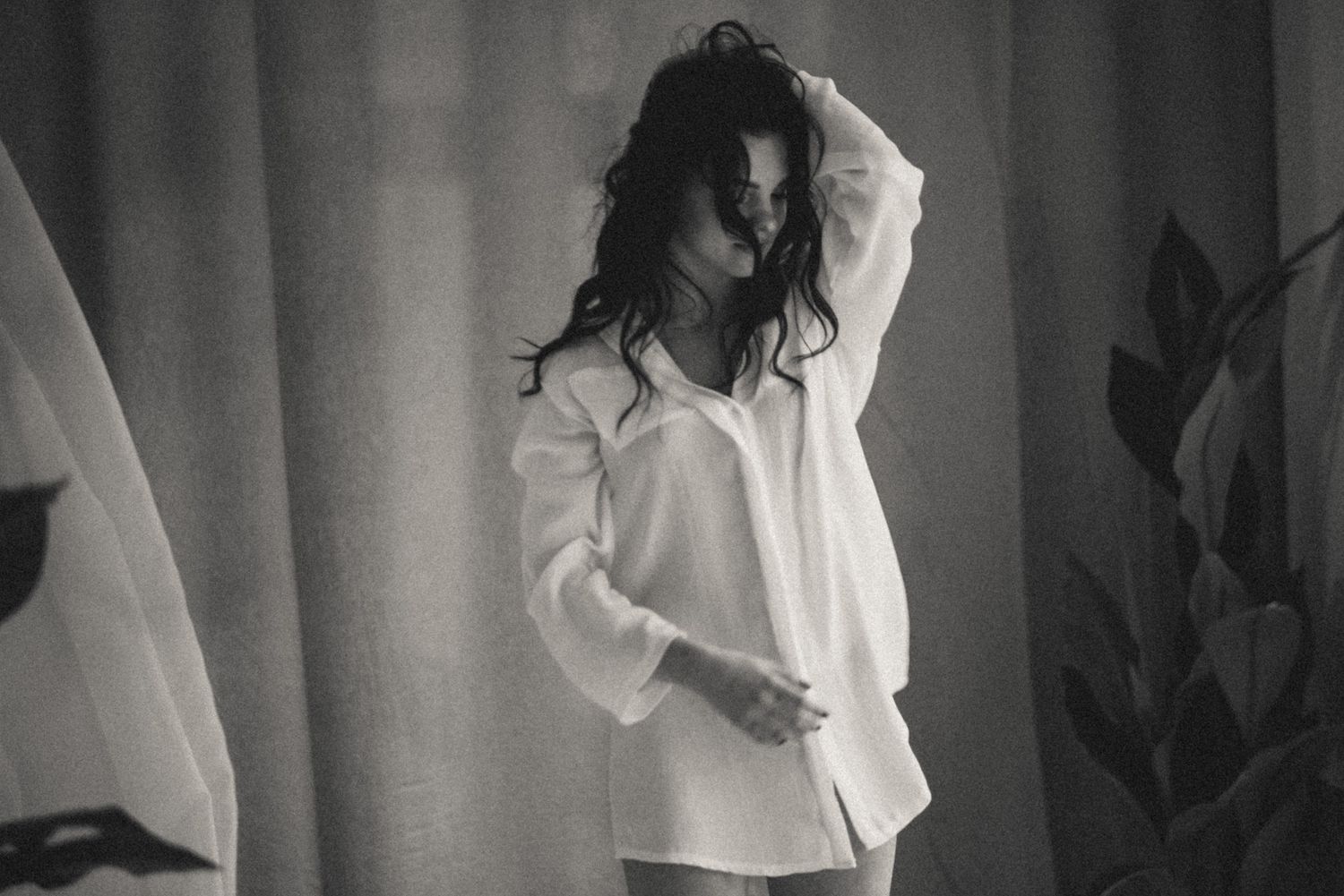 Woman in oversized white shirt posing naturally, candid morning light boudoir session in Amsterdam.