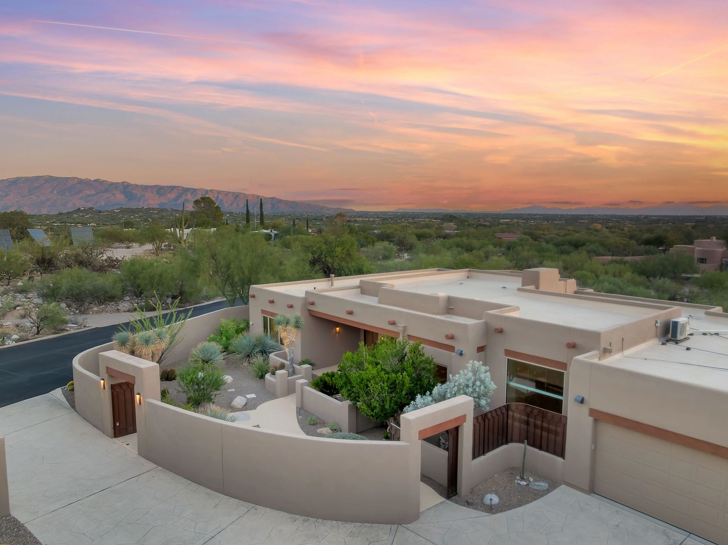 Stunning sunset panorama over desert landscape with adobe buildings and mountain silhouettes.