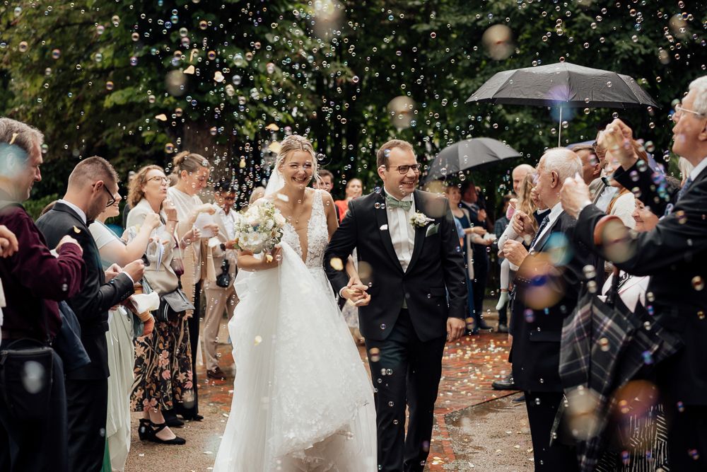 A romantic wedding couple embraces in sunlit garden setting at golden hour.