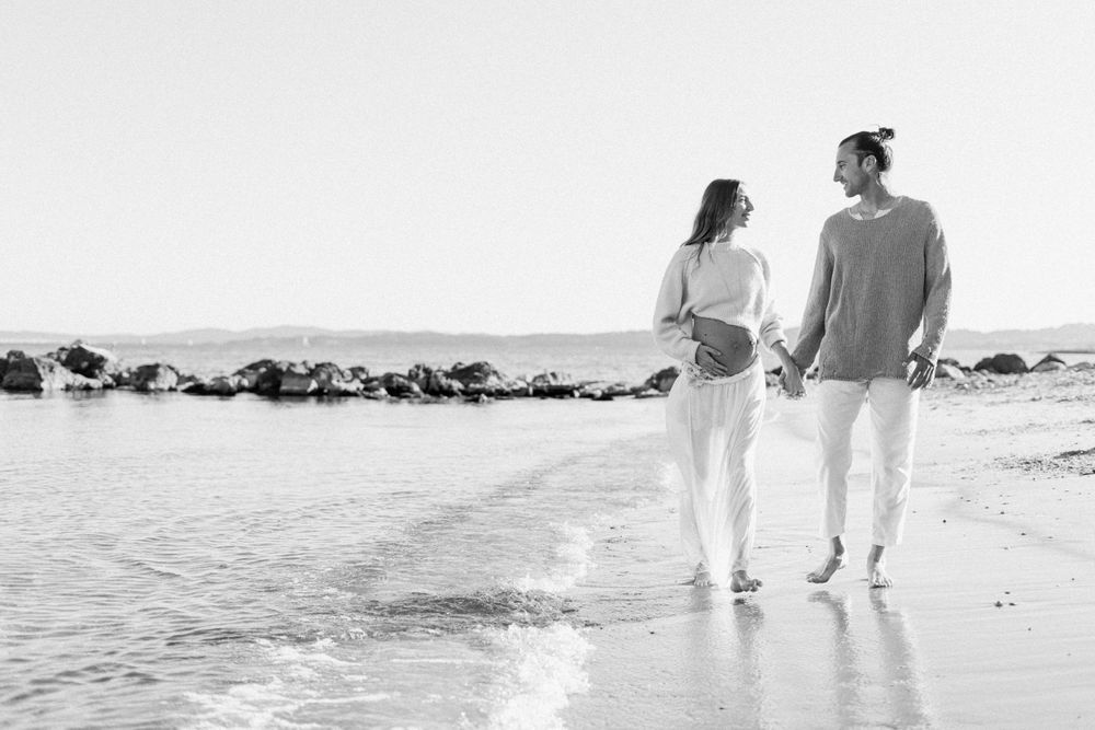 A couple walking together along a beach shoreline in black and white photography.