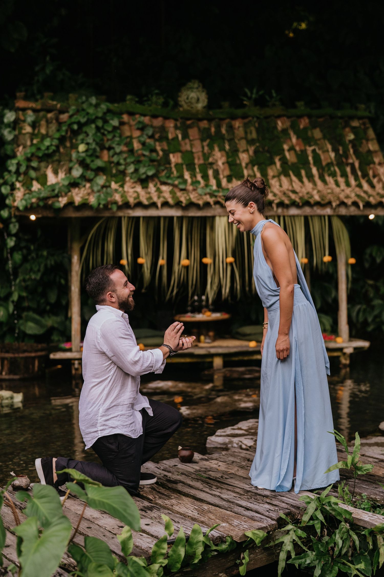 Couple walking along a green garden pathway surrounded by tropical plants.