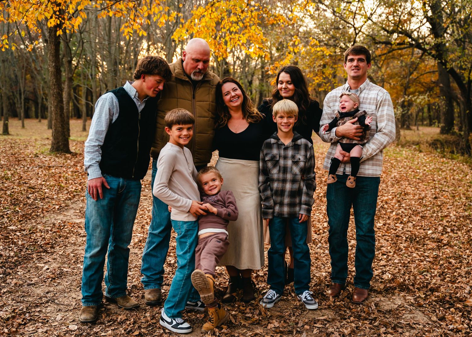 Family enjoying autumn season together in a park with golden fallen leaves on the ground.