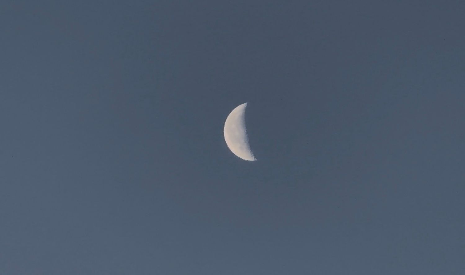 Four sequential images show the moon in different phases against a deep blue evening sky.