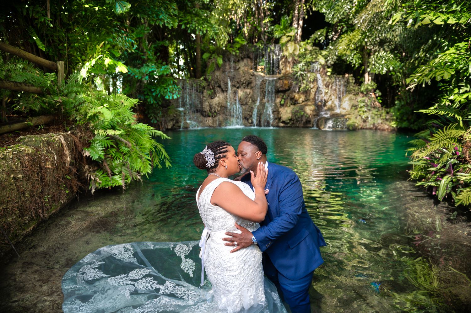 The groom kisses his bride in the water at the Secret Gardens Miami wedding venue.