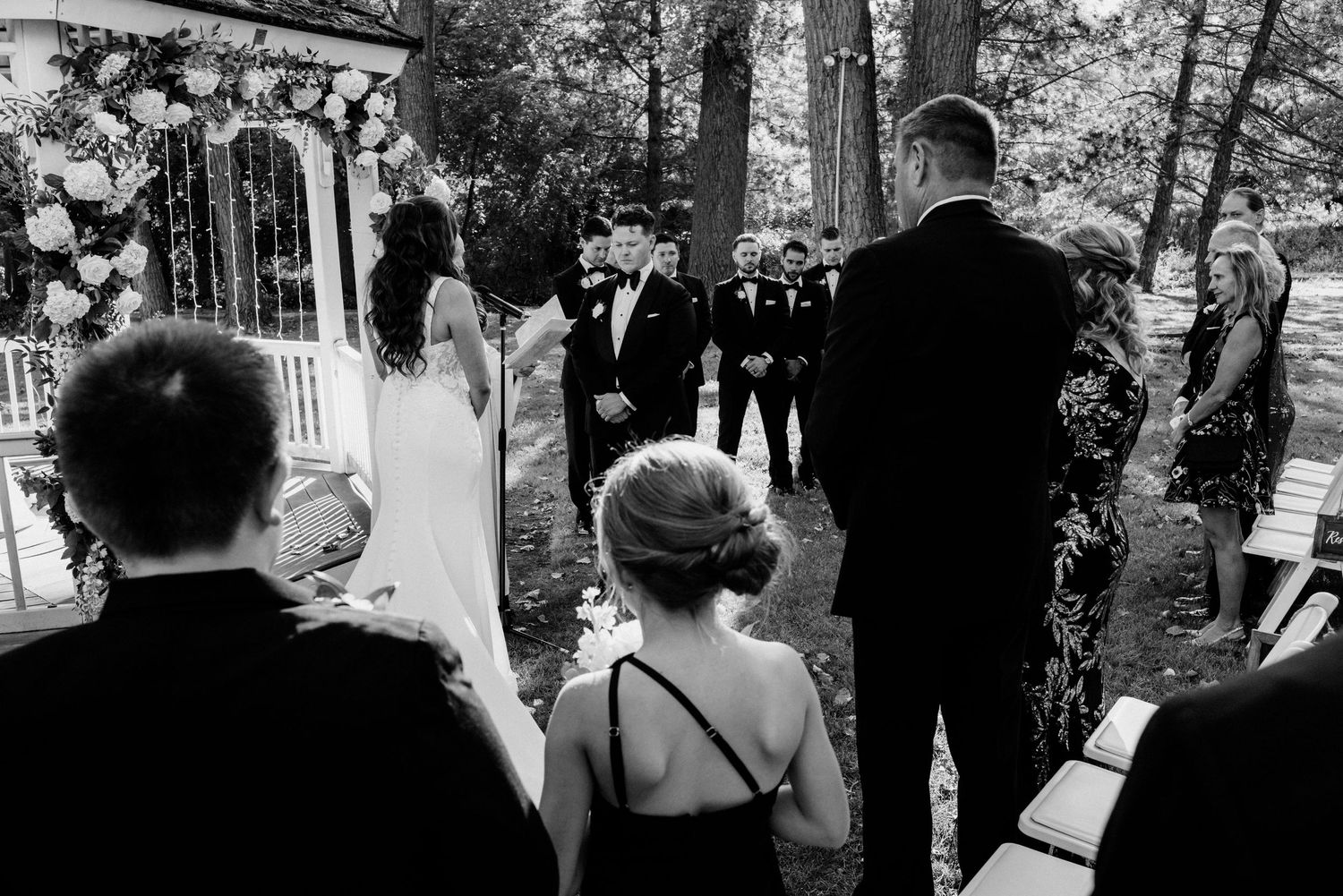 Elegant outdoor evening wedding reception under illuminated tent with candlelit tables at night.