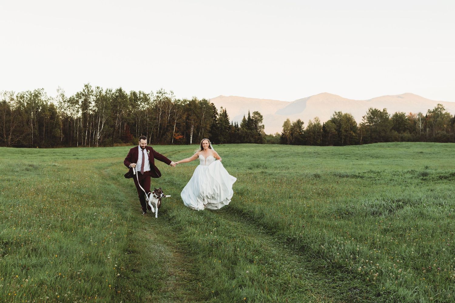 Bride and groom running together through a field on their wedding day.